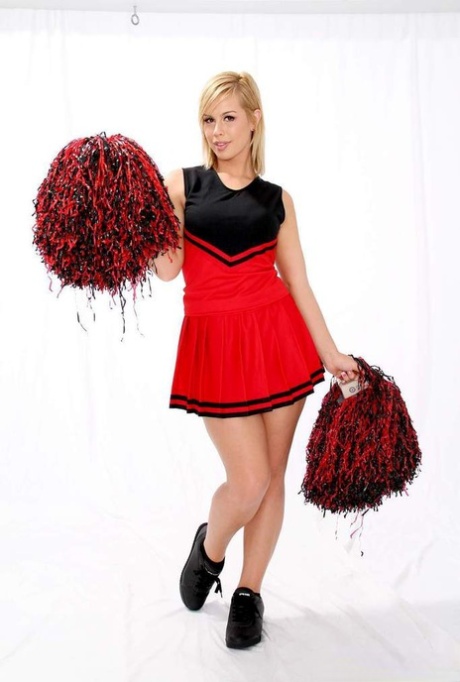 Blonde cheerleader puts down her pom poms and takes off her clothes