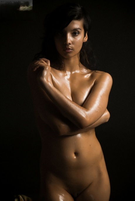 Mulher indiana nua expõe um único seio enquanto modela no escuro