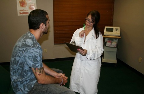 Söt brunettsköterska i glasögon ger ett sensuellt handjob till en lycklig kille