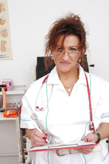 Skitten, moden sykepleier med briller tar av seg trusa og blottlegger fitta.