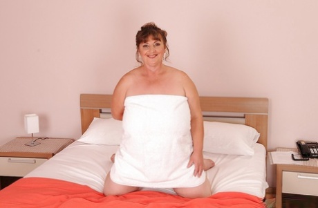 Mulher madura com mamas enormes e flácidas e coiro peludo a posar na cama