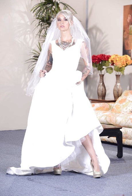 Una splendida sposa bionda in un abito glamour che scopre le sue curve tatuate