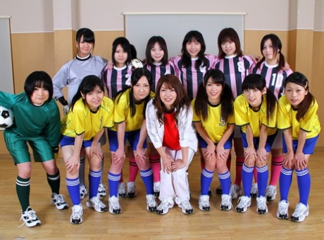 Asiatisk kvindefodboldhold ser på, mens en holdkammerat bliver kneppet af dommerne
