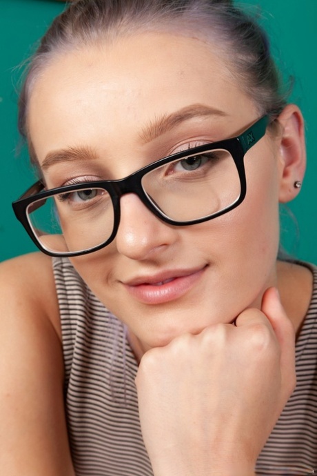 Sexy adolescente en gafas Ellie Kay toca su coño peludo después de desnudarse