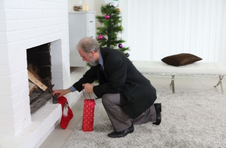 Schattige mevrouw de kerstman Loventa wordt geslagen door een oude man bij de open haard