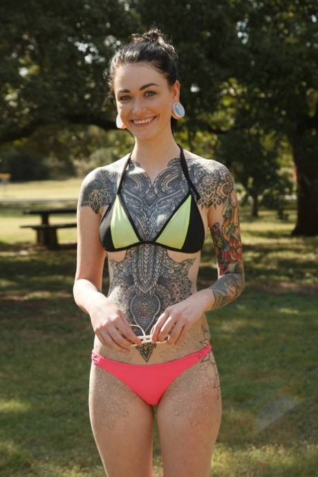 La petite amie encrée Kelly Lamprin expose ses petits seins et son cul dans le parc