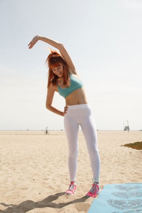 Sexy roodharige Penelope Lynn plaagt operator terwijl ze yoga doet op het strand