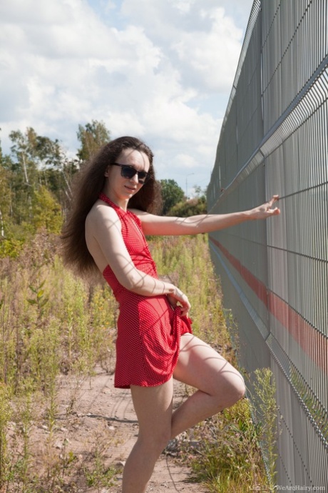Lisa Li, branca e magra, tira o vestido vermelho e cuecas do exterior da cerca composta