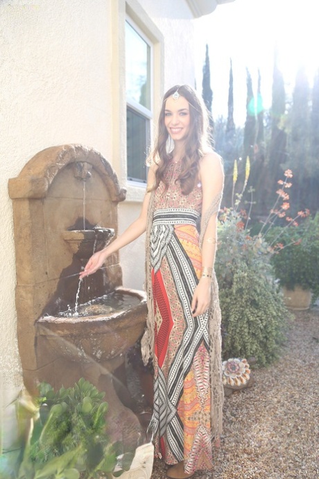 Tali Dova, beauté brune et bohème, pose dans sa robe hippie dans le jardin.