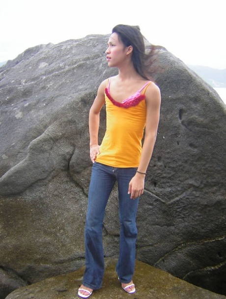 Lekkere Thaise shemale stript en masturbeert terwijl ze op een rots staat