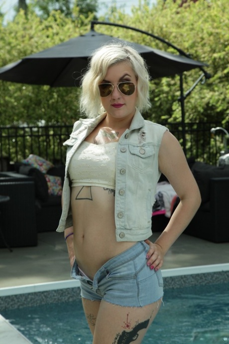 Tattooed blonde chick Violet Revolver taking her clothes off by the pool