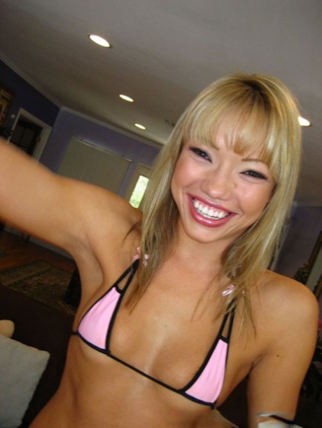 Piękna uśmiechnięta blondynka azjatycka Maya Hills w bikini głęboko gardłuje banana