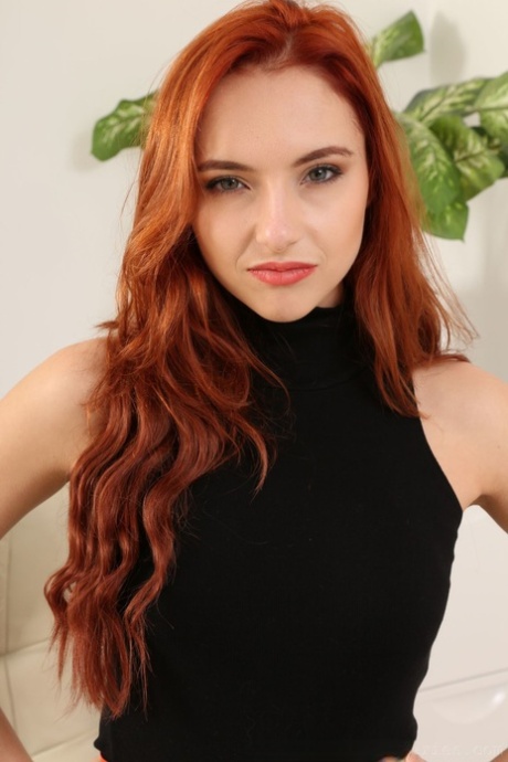 Modellen Sophia Blake med rött vågigt hår klär av sig och poserar i genomskinliga strumpbyxor