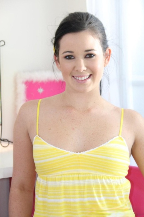 Amy Starz, uma adolescente sorridente, tira a sua roupa amarela e mostra pequenas mamas