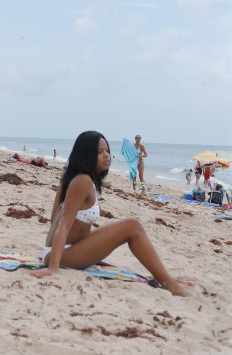 Beautiful young ebony Nina Belle with big tits sunning on the beach in bikini