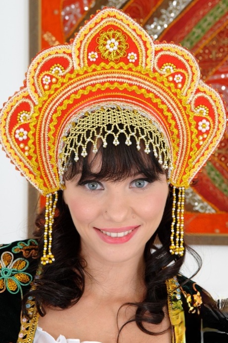 Russische schoonheid ontdoet zich van traditionele kleding om naakt te poseren met hakken en hoofdtooi