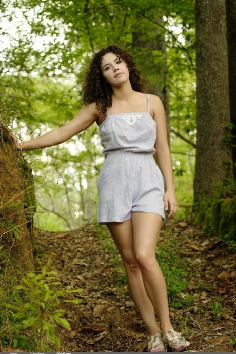 Rapariga solitária com cabelo encaracolado exibe o seu arbusto espesso na floresta