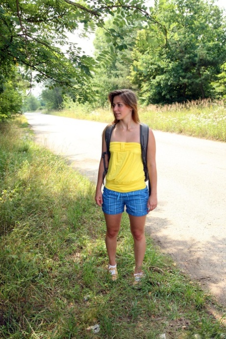 Die kaukasische Teenagerin Bella E. steht nackt auf einer Straße, nachdem sie unter einem Baum masturbiert hat
