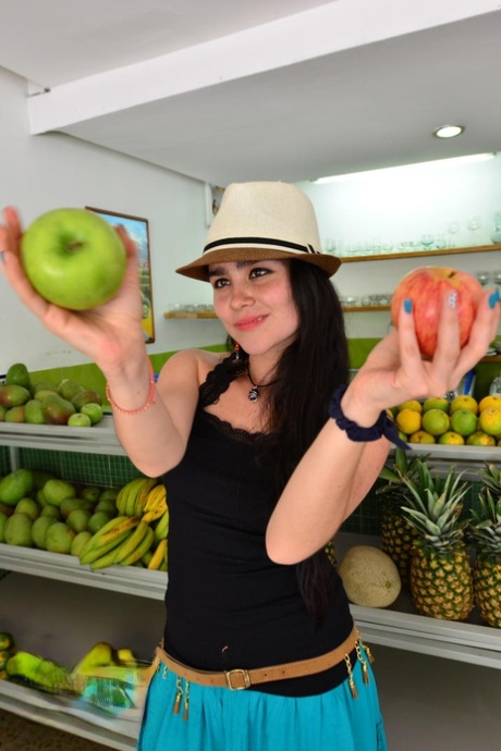 Mooi Colombiaans meisje eet fruit en schilt neer om naakt te poseren in hoed en riem