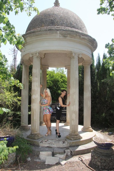 Zwei eingeölte lesbische Babes benutzen einen doppelendigen Dildo zusammen in der Gartenlaube Ruinen
