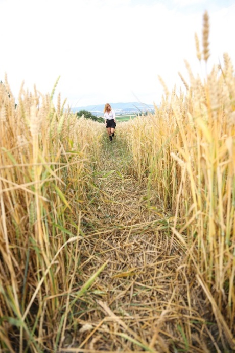 A estudante loira Chrissy Fox dedilha a sua rata careca no meio de um campo de trigo