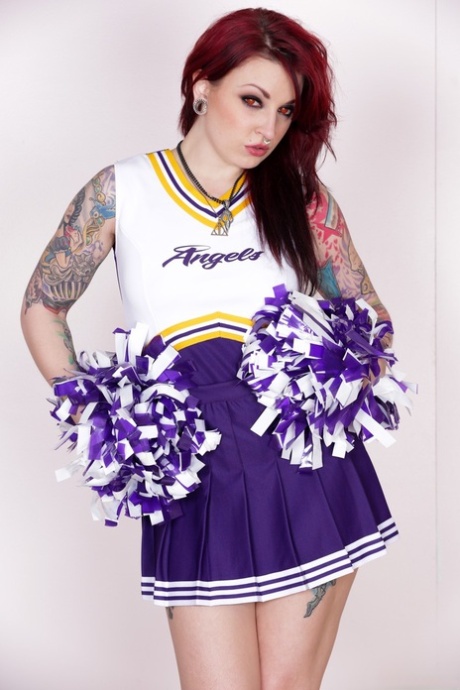 La pom-pom girl tatouée Draven Star enlève son uniforme et pose chaudement.