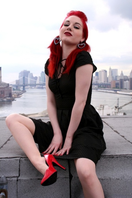 Rødhåret modell stripper i nylonstrømper og høyhælte sko på et hustak