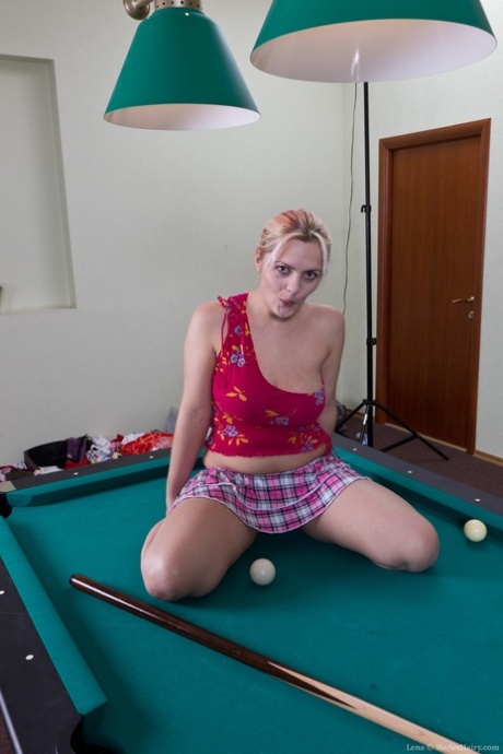 Lena, blonde plantureuse, baise sa chatte touffue avec une queue de billard sur une table de billard.