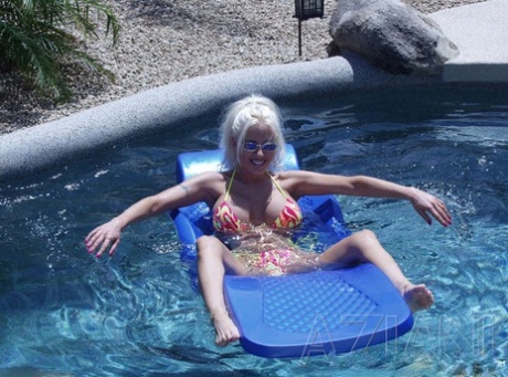 Tynd blondine med store falske bryster Kelly Erikson viser sin fisse i poolen