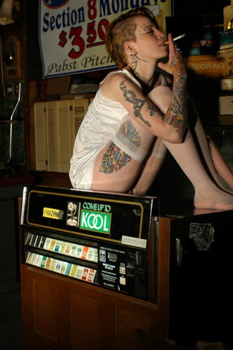 Babe with short hair and heavy tattoos is a striptease at an empty bar