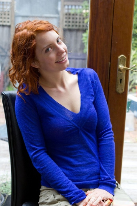Söt rödhårig Kara Dashka visar sina bleka naturliga bröst och sprejer i fönstret