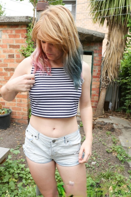 Соло девушка с разноцветными волосами Офелия Роуз обнажает свой клитор в саду