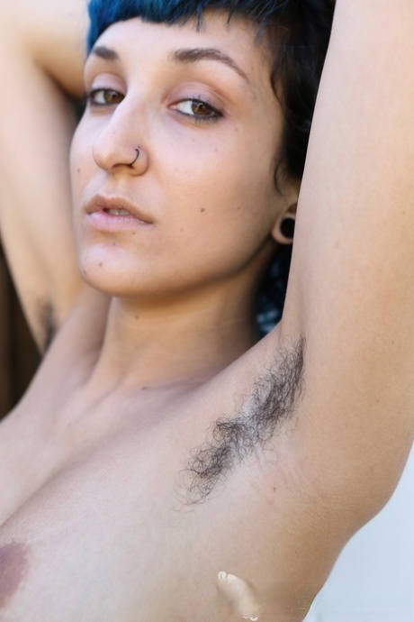 Blue haired vixen Jay Elle flaunts her hairy armpits and pussy while stripping