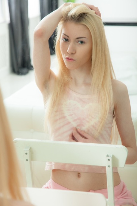 Erica, blonde aux petits seins, joue avec son vibrateur préféré sur une chaise.