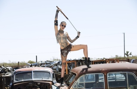 Tattooed shaved headed Leigh Raven goes topless and poses at the salvage yard