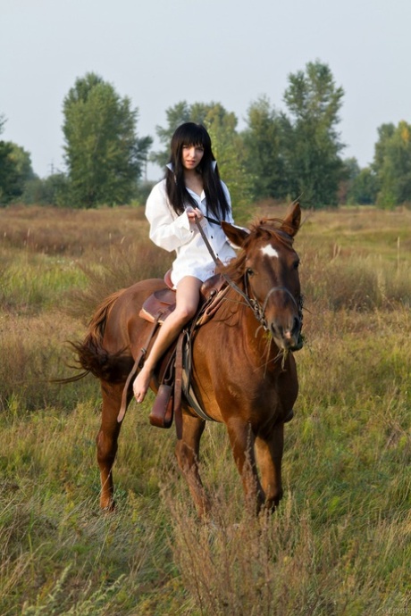 Milania A posa desnuda con su caballo favorito en el campo