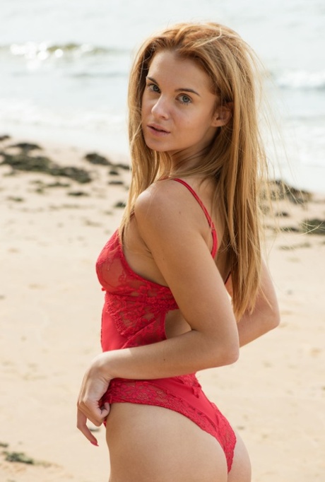 Schattige tiener in een kanten bodysuit Ingrid pronkt met haar slanke lichaam op het strand