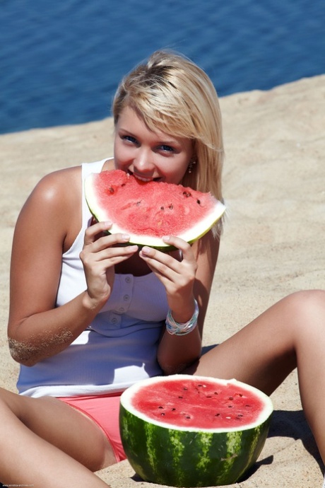 Schattig Blondine Lada displays haar mooie geschoren kutje op een zandstrand