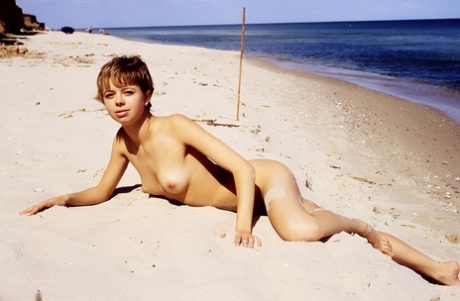 Krótkowłosa nastolatka Olga rozciąga swoją łysą cipkę na piaszczystej plaży