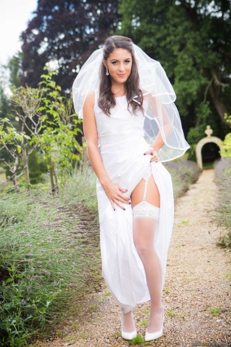 Smal brunett i bröllopsklänning Carolina Abril visar naturliga bröst och rumpa