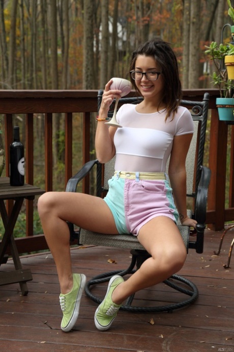 A adolescente sorridente Daisy Haze insere uma garrafa de vinho na sua rata de cavilha ao ar livre