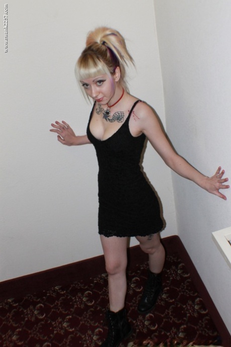 Die tätowierte Blondine Symone stellt ihre sexy Beine in einem kurzen schwarzen Kleid und Stiefeln zur Schau