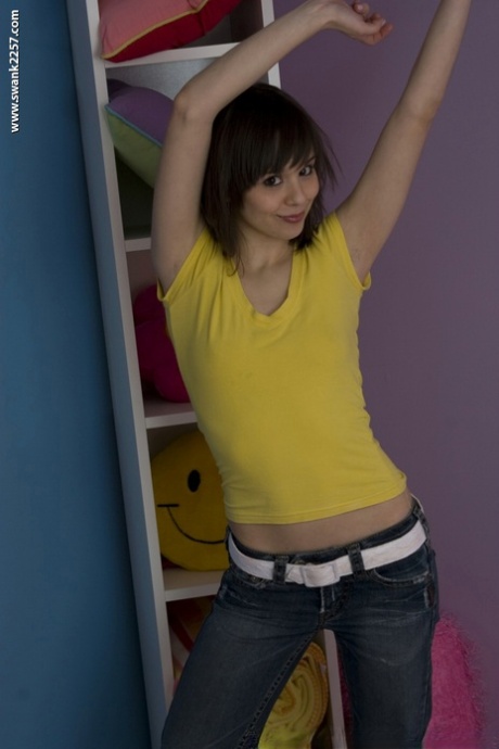 La petite MILF Ariel Rebel pose dans sa chemise jaune et ses jeans serrés.