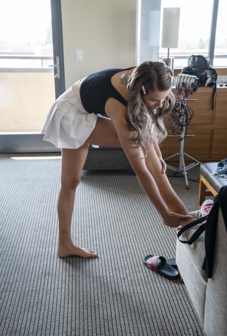 Adorável adolescente em uma saia curta Chanel Grey expõe seu corpo em um quarto de hotel