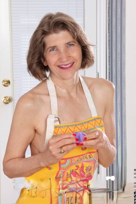 Bobby Bentley, femme au foyer mature et impertinente, joue avec un rouleau à pâtisserie en portant un tablier.