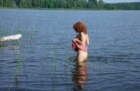 Сексуальная крошка с большой попкой Sunny раздевается догола для соло игры в воде в озере