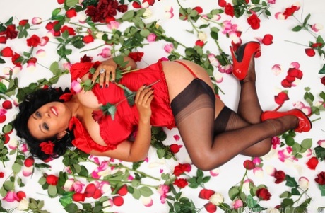 La sexy MILF in calze di nylon Danica Collins stuzzica le sue tettone sul letto a fiori