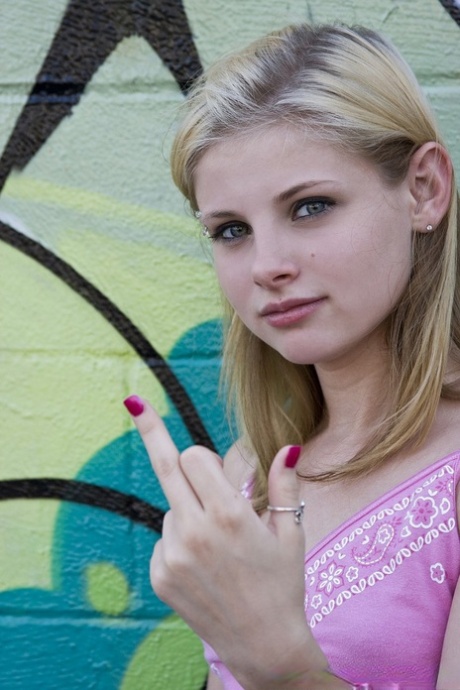 Blond teenager med attitude viser sine små bryster og skaldede fisse i en udendørs solo