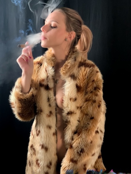 Blonde with a ponytail poses in her fur coat as she smokes a cigarette