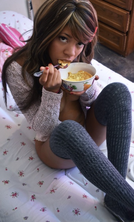 Bambina nera con calze grigie La piccola Yumi mostra le sue tette mentre mangia su un letto